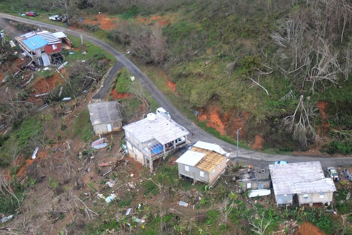 People wave from the roof of a house in Jayuya, Puerto Rico, to signal helicopter crew for help, Puerto Rico, Oct. 14, 2017. (Photo: U.S. Coast Guard Senior Chief Petty Officer Kyle Niemi)
