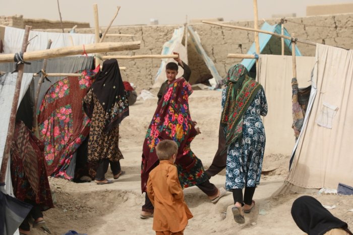 Afghan women walking among tents