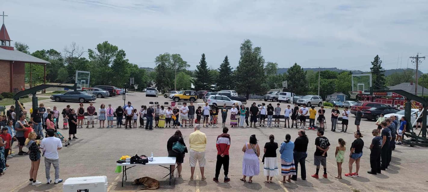 People stand in a circle for an opening prayer outside the Daron White Eagle Teen Center.