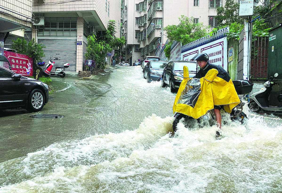 Male wearing a yellow poncho riding a motorcycle on a flooded street