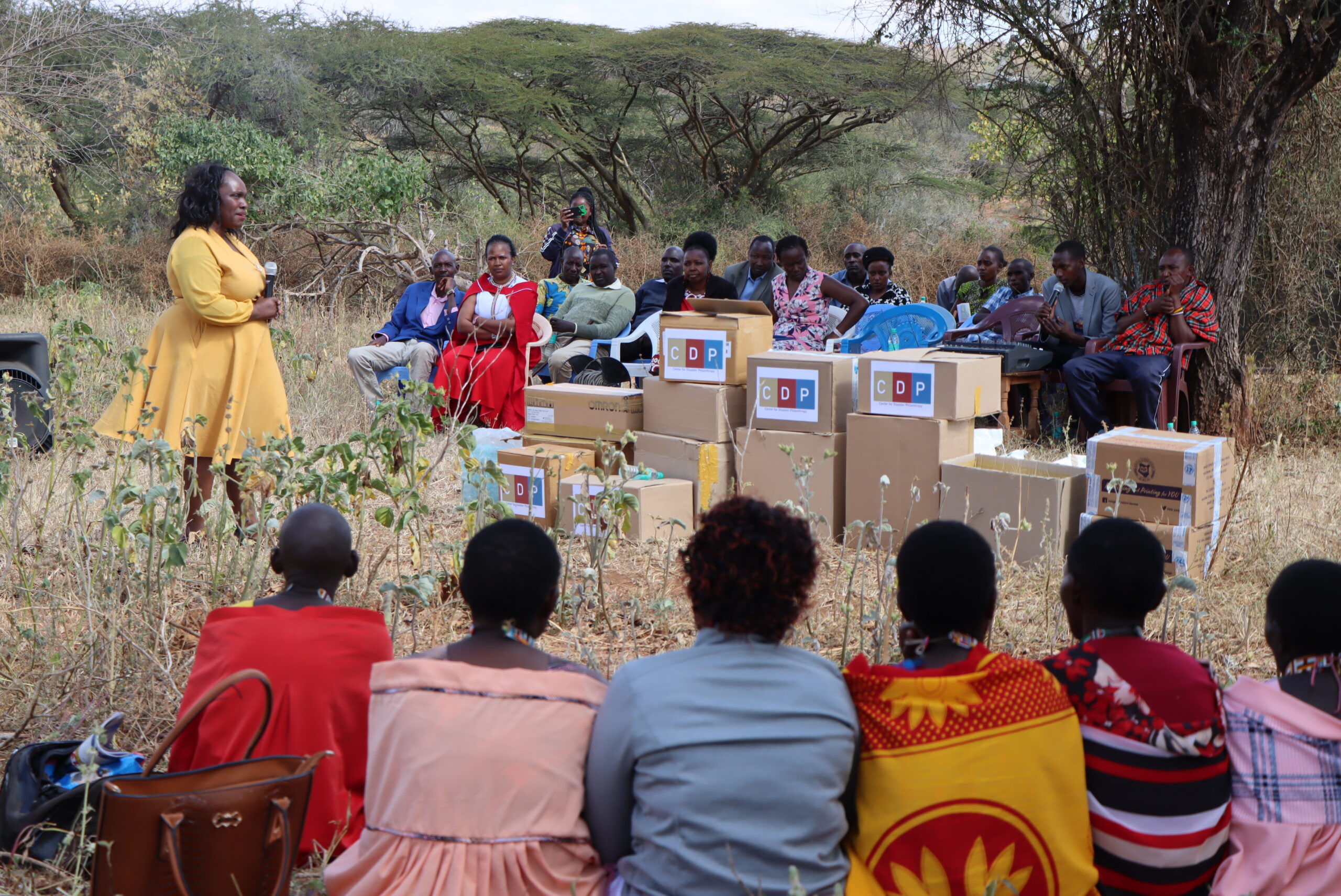 Women in a field watching a speaker give a presentation