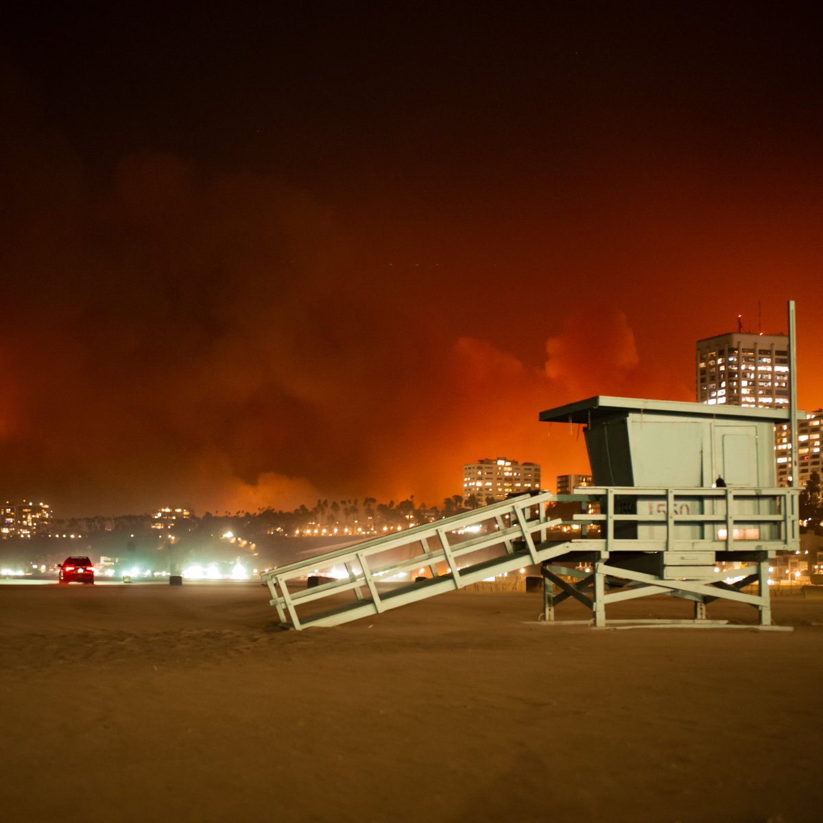 lifeguard stand on a beach at night with wildfires burning in the background