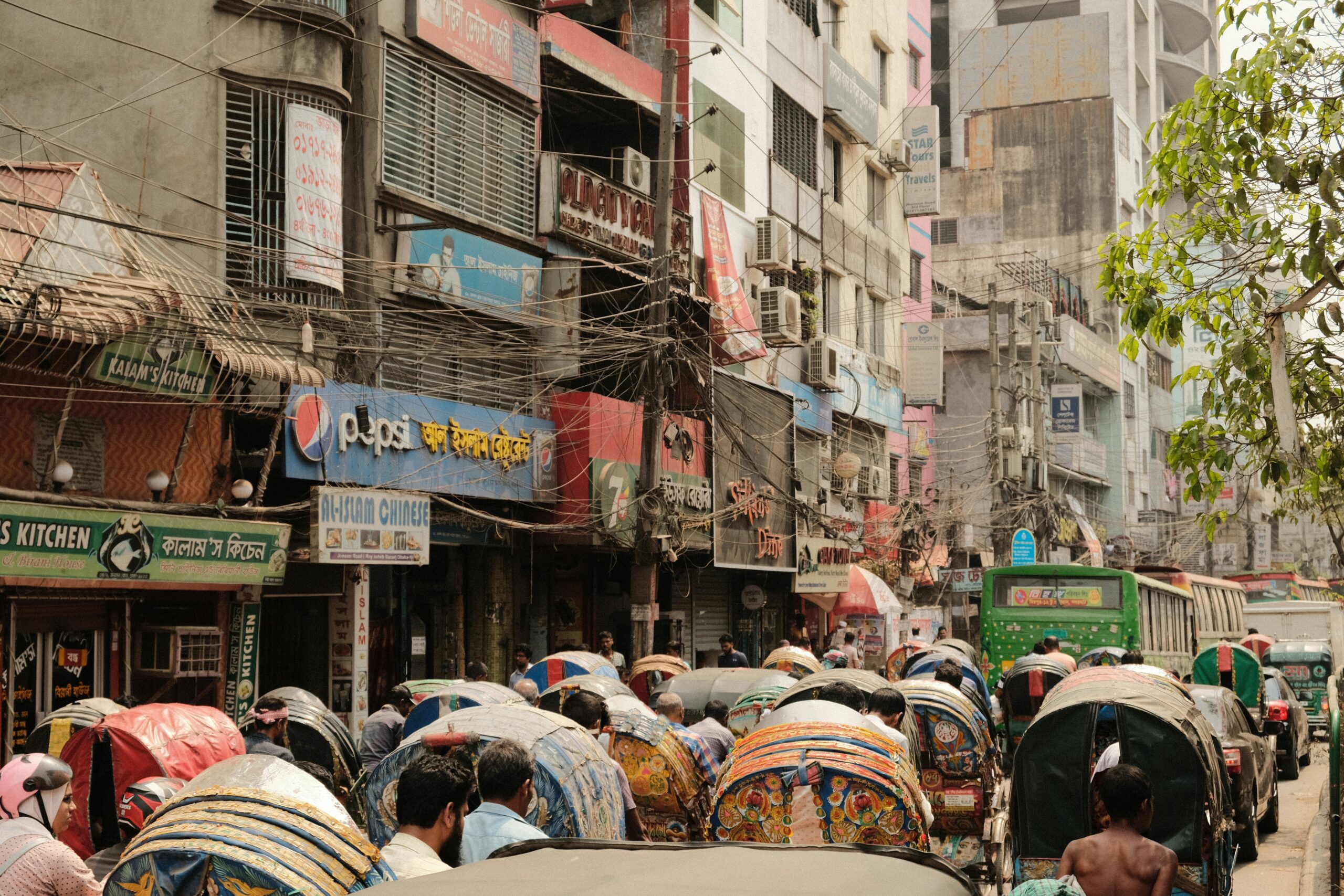 A group of people walking down a street with umbrellas in Dhaka, Bangladesh.